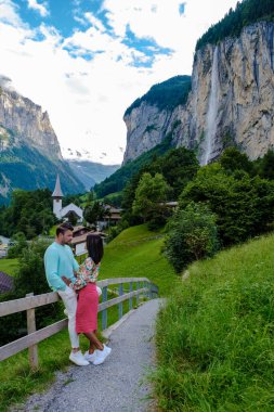 Lauterbrunnen Vadisi 'nde muhteşem bir şelale ve arka planda İsviçre Alpleri olan Berner Oberland, İsviçre ve Avrupa' yı ziyaret eden iki erkek ve kadın.. 