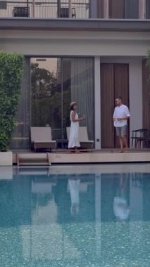 Asya 'da lüks 5 yıldızlı otel havuzu. Lüks bir otelde tatil yapan bir çift erkek ve kadın, tatil yerinin havuzunun yanındaki erkekler ve kadınlar