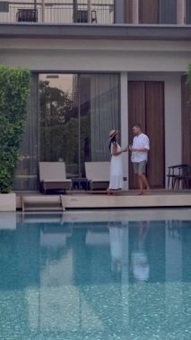 Asya 'da lüks 5 yıldızlı otel havuzu. Lüks bir otelde tatil yapan bir çift erkek ve kadın, tatil yerinin havuzunun yanındaki erkekler ve kadınlar