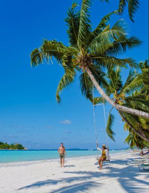 Praslin Seyşeller tropikal adasında beyaz plajlar ve palmiye ağaçları, hamaklardaki birkaç kadın ve erkek Anse Volber Seyşeller 'deki bir palmiye ağacının altında sallanıyorlar..