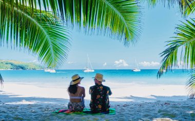 Praslin Seyşeller tropikal adası, plajları geniş ve palmiye ağaçları olan, orta yaşlı bir çift erkek ve kadın Seyşeller 'de tatilde tropikal sahil Anse Lazio Praslin Seyşeller' i ziyaret ediyor. Drone görünümü