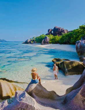 Anse Source dArgent plajı, La Digue Adası, Seyşeller, gün batımında sahilde yürüyen birkaç erkek ve kadın...