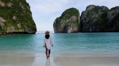 Maya Körfezi sahilinde yürüyen Taylandlı kadınlar Koh Phi Phi Tayland, sabahın erken saatlerinde sahilde turistsiz ve turkuaz renkli okyanussuz. 