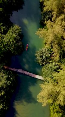 Tropikal ada Koh Chang Tayland 'da kano süren bir çift kadın ve erkek, güneş batarken Koh Chang ormanındaki tropikal bir nehirde kano manzaralı.