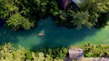 Tropikal ada Koh Chang Tayland 'da kano süren bir çift kadın ve erkek, güneş batarken Koh Chang ormanındaki tropikal bir nehirde kano manzaralı.