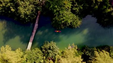 Tropikal ada Koh Chang Tayland 'da kano süren bir çift kadın ve erkek, güneş batarken Koh Chang ormanındaki tropikal bir nehirde kano manzaralı.