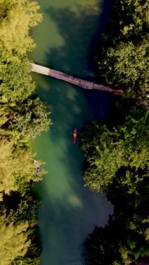 Tropikal ada Koh Chang Tayland 'da kano süren bir çift kadın ve erkek, güneş batarken Koh Chang ormanındaki tropikal bir nehirde kano manzaralı.