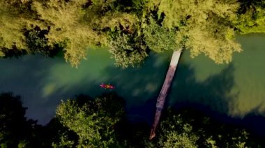 Tropikal ada Koh Chang Tayland 'da kano süren bir çift kadın ve erkek, güneş batarken Koh Chang ormanındaki tropikal bir nehirde kano manzaralı.
