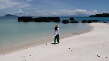 Koh Chang bölgesinde Koh Mak yakınlarındaki Koh Kham Adası 'nın kumsalında bir kadın. Tayland' da beyaz plajı ve turkuaz renkli okyanusu olan tropikal bir ada..
