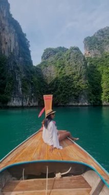 Uzun kuyruklu botlar Pileh Lagoon Koh Phi Phi Maya Körfezi Tayland 'da, Asya' lı kadınlar Koh Phi Phi Maya Körfezi 'ne giderken uzun kuyruklu botların önünde.