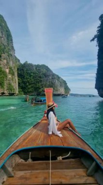 Uzun kuyruklu botlar Pileh Lagoon Koh Phi Phi Maya Körfezi Tayland 'da, Asya' lı kadınlar Koh Phi Phi Maya Körfezi 'ne giderken uzun kuyruklu botların önünde.