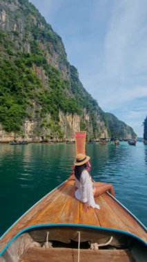 Uzun kuyruklu botlar Pileh Lagoon Koh Phi Phi Maya Körfezi Tayland 'da, Asya' lı kadınlar Koh Phi Phi Maya Körfezi 'ne giderken uzun kuyruklu botların önünde.