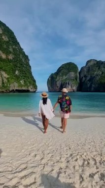 Koh Phi Phi Maya Körfezi Tayland, Koh Phi Phi 'de turkuaz renkli okyanusla sahilde yürüyen bir çift kadın ve erkek. 