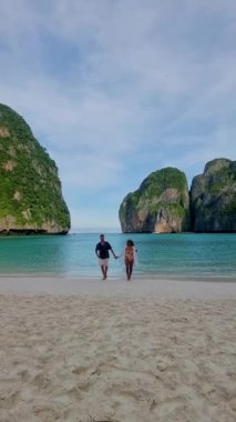 Koh Phi Phi Adası Maya Körfezi 'ne tekne gezisi sırasında turkuaz renkli okyanusla sahilde yürüyen bir çift orta yaşlı erkek ve kadın.