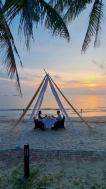 Tayland 'da Koh Chang Adası' nda gün batımında romantik bir akşam yemeği yiyen bir çift erkek ve kadın.. 