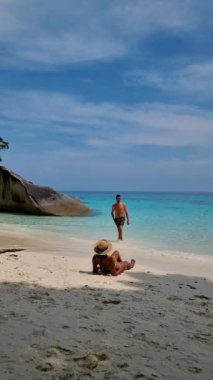 Similan Adaları Tayland, turkuvaz renkli okyanusları olan tropikal bir plaj, Similan Adaları 'na tekne gezisinde birkaç erkek ve kadın, beyaz plajda güneşleniyorlar.
