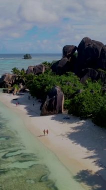 Anse Source dArgent, La Digue Seychelles, Seyşeller 'de lüks bir tatil sırasında tropikal plajda bir çift. Tropik sahil Anse Kaynağı dArgent, Gün batımında La Digue Seyşeller