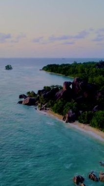 Günbatımında Anse Source dArgent plajı, Seyşeller 'de lüks bir tatilde günbatımında tropikal bir plaj olan La Digue Seychelles. Tropik sahil Anse Kaynağı dArgent, Gün batımında La Digue Seyşeller