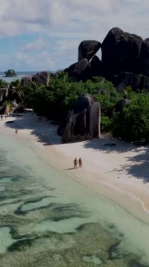 Anse Source dArgent, La Digue Seychelles, Seyşeller 'de lüks bir tatil sırasında tropikal plajda bir çift. Tropik sahil Anse Kaynağı dArgent, Gün batımında La Digue Seyşeller