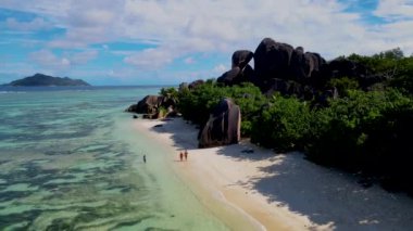 Anse Source dArgent, La Digue Seychelles, Seyşeller 'de lüks bir tatil sırasında birkaç beyaz erkek ve Asyalı kadın plajı. Tropik sahil Anse Kaynağı dArgent, La Digue Seyşeller at