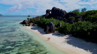 Anse Source dArgent, La Digue Seychelles, Seyşeller 'de lüks bir tatil sırasında birkaç erkek ve kadın tropikal plajı. Tropik sahil Anse Kaynak dArgent, La Digue Seyşeller 