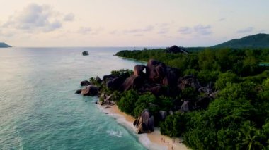 Anse Source dArgent, La Digue Seychelles, Seyşeller 'de lüks bir tatil sırasında tropik bir plajda gün batımını izleyen birkaç kadın ve erkek. Anse Kaynak dArgent, Gün batımında La Digue Seyşeller