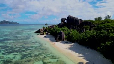 Seyşeller 'de lüks bir tatil sırasında Anse Source DArgent, La Digue Seychelles plajında yürüyen çift.