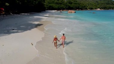 Seyşeller 'de lüks bir tatil sırasında tropik bir plajda yürüyen genç bir çift olan Anse Lazio Praslin Seyşeller plajında yürüyor. Tropik plaj Anse Lazio Praslin Seyşeller