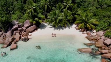 Anse Lazio Praslin Seyşeller. Tropikal bir plajda, palmiye ağaçları ve turkuaz renkli okyanuslarla lüks bir tatil yapan genç bir çift.