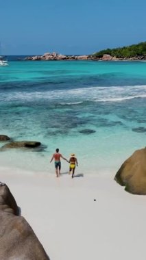 Anse Cocos plajı la Digue Seychelles, birkaç adam tropik ada La Digue Seyşeller 'de mayo giyip okyanusta yürüyorlar.