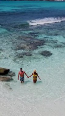 Anse Cocos plajı la Digue Seychelles, birkaç adam tropik ada La Digue Seyşeller 'de mayo giyip okyanusta yürüyorlar.