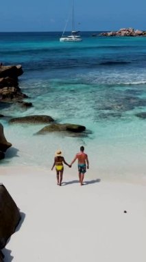 Anse Cocos plajı la Digue Seychelles, birkaç adam tropik ada La Digue Seyşeller 'de mayo giyip okyanusta yürüyorlar.
