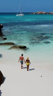 Anse Cocos plajı la Digue Seyşeller, tropikal ada La Digue Seyşeller 'de mayo giymiş iki adam okyanusta yürüyor.