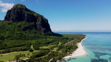 Le Morne plajı Mauritius Tropikal plajı. Palmiye ağaçları, beyaz kum mavisi okyanus ve şemsiyeli plaj yatakları, güneş sandalyeleri ve tropik bir sahildeki palmiye ağacının altında şemsiyeler. Mauritius 