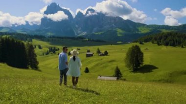 Seiser Alm Sassolungo Langkofel dağ grubuyla birlikte gün batımında Alpe di Siusi Dağı 'nda. İtalya 'nın Dolomitler Dağları' nda gün batımını izleyen bir çift erkek ve kadın.