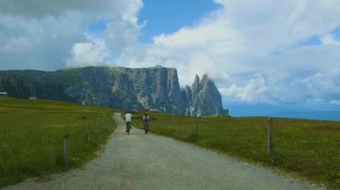 Seiser Alm Sassolungo Langkofel dağ grubuyla birlikte gün batımında Alpe di Siusi Dağı 'nda. İtalya 'nın Dolomitler dağlarında birkaç erkek ve kadın bisikleti.
