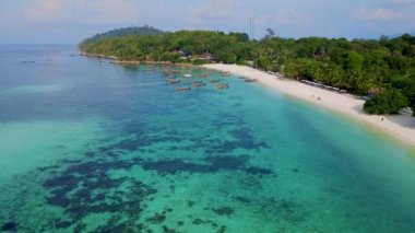 Tayland 'ın Koh Lipe şehrinde güneşli bir günde, turkuaz renkli okyanusta uzun kuyruklu teknelerin Koh Lipe Adası manzarası. Kumsaldaki hava aracı görüntüsü.