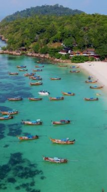 Tayland 'ın Koh Lipe şehrinde güneşli bir günde, turkuaz renkli okyanusta uzun kuyruklu teknelerin Koh Lipe Adası manzarası. Kumsaldaki beyaz kumlu hava aracı görüntüsü.