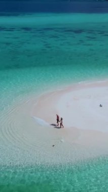 Koh Lipe Tayland 'da tatilde olan birkaç beyaz erkek ve Taylandlı kadın Koh Lipe Lipe' nin mercan kayalığındaki bir kumsalda yürüyorlar.