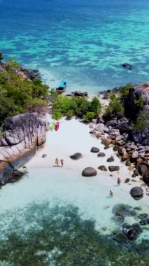 Birkaç erkek ve kadın Koh Lipe Tayland 'da tatildeler. Uzun kuyruklu tekneler ve kanolar Kla Adası' nın Koh Lipe kentindeki küçük bir adada.