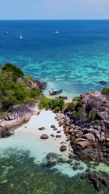 Birkaç erkek ve kadın Koh Lipe Tayland 'da tatildeler. Uzun kuyruklu tekneler ve kanolar Kla Adası' ndaki Koh Lipe adasının önündeki küçük bir adada.