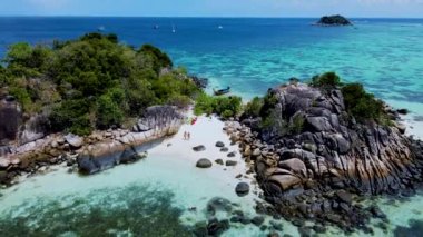 Birkaç erkek ve kadın Koh Lipe Tayland 'da tatildeler. Uzun kuyruklu tekneler ve kanolar Kla Adası' nın Koh Lipe kentindeki küçük bir adada.