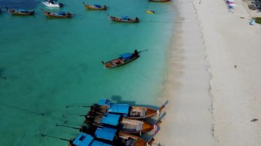 Tayland 'daki Koh Lipe Adası' nda güneşli bir günde turkuaz renkli okyanusta uzun kuyruklu teknelerin hava manzarası. Kumsaldaki hava aracı görüntüsü.