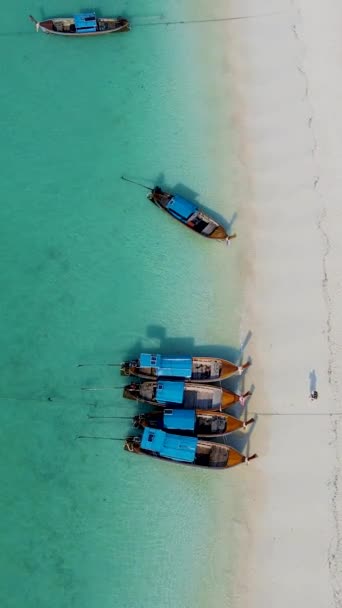 在泰国的Koh Lipe岛上 在一个阳光灿烂的日子里 泰国的Koh Lipe从空中俯瞰着蓝绿色海洋中的长尾船 白色沙滩上的无人机俯瞰 — 图库视频影像