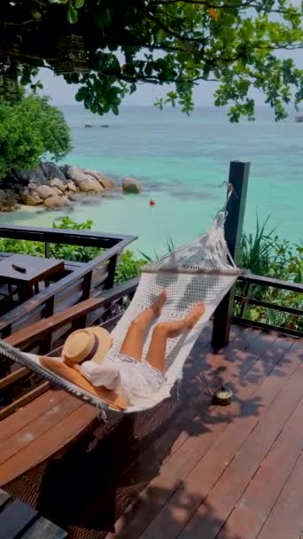 Koh Lipe泰国亚洲女人在海滩上的一个吊床里 俯瞰着Koh Lipe Thailand的草屋色大海 — 图库视频影像