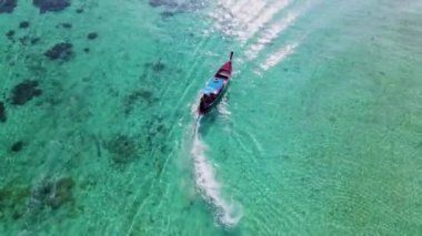 Tayland 'daki Koh Lipe Adası' nda güneşli bir günde turkuaz renkli okyanusta uzun kuyruklu teknelerin hava manzarası. Beyaz kum ve mavi okyanusla kumsalda drone hava manzarası