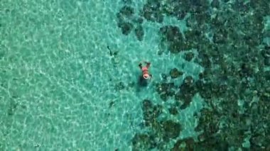 Mercan resifinde yüzen Asyalı kadınlar, Tayland 'ın Trang kentindeki Koh Kradan adasının havadan görünüşü. Mercan resifi ve turkuaz renkli okyanus drone manzaralı tropik plaj.