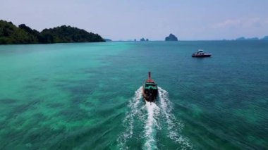 Tayland 'ın Trang kentindeki Koh Kradan adasının mavi okyanusundaki uzun kuyruklu teknelerin hava manzarası. Yazın mavi okyanusta uzun kuyruklu teknelerle mercan resifi ve turkuaz renkli okyanusu olan tropik bir sahil.