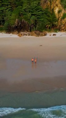 Tayland, Trang 'daki Koh Kradan adasının havadan görüntüsü. Yaz boyunca mercan kayalıkları ve turkuaz renkli okyanusları olan tropik plajlar, gün batımı plajında birkaç erkek ve kadın.