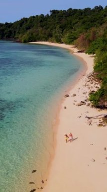 Tayland, Trang 'daki Koh Kradan Adası' nda tatil yapan bir çift. Yaz boyunca mercan kayalıkları ve turkuaz renkli okyanusları olan tropik plaj, Koh Kradan Adası 'ndaki plajda birkaç erkek ve kadın.